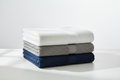 Soft bath towels in white, gray, and navy blue neatly folded on a white background